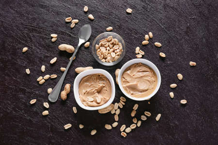 Bowls with tasty peanut butter on dark backgroundの写真素材