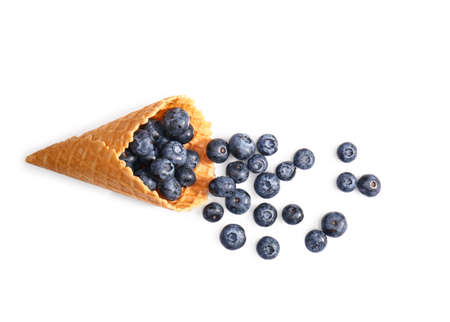 Wafer cone with tasty ripe blueberries on white background