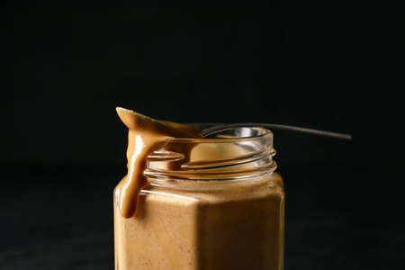 Jar with tasty peanut butter on dark backgroundの写真素材