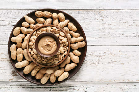 Tasty peanut butter with nuts on table