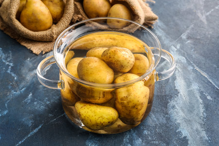 Cooking pot and bags with raw potatoes on color backgroundの写真素材