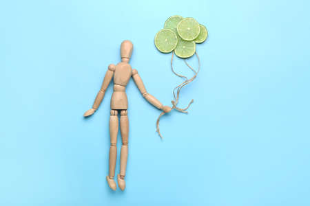 Composition with wooden human mannequin and lime slices on color backgroundの写真素材