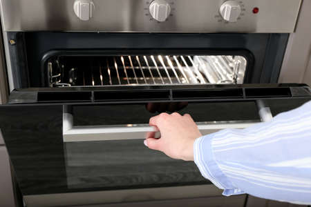 Woman opening oven in kitchen