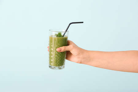 Hand with healthy vegetable smoothie on color backgroundの写真素材