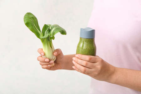 Woman with healthy vegetable smoothie on light background, closeupの写真素材