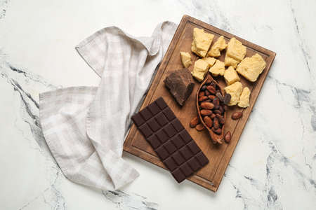 Board with cocoa butter, chocolate and beans on light backgroundの写真素材