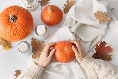 Woman with pumpkins and candles on light backgroundの写真素材