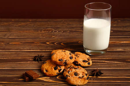 Tasty chocolate chips cookies with milk on wooden tableの写真素材