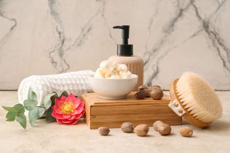 Bowl with shea butter, nuts and bath supplies on light backgroundの写真素材