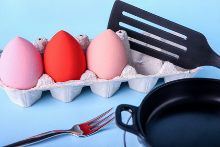 Creative composition with eggs holder, makeup sponges and kitchen utensils on color background, closeupの写真素材