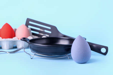 Creative composition with eggs holder, makeup sponges and kitchen utensils on color backgroundの写真素材