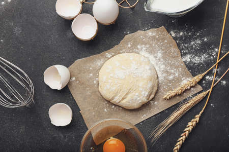 Fresh dough with ingredients for preparing bakery and utensils on dark backgroundの写真素材