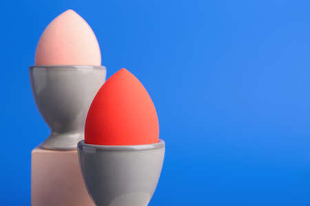 Creative composition with egg holders and makeup sponges on color backgroundの写真素材