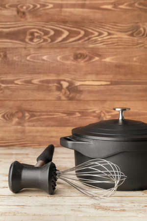 Cooking pot with whisk and hammer on wooden backgroundの写真素材