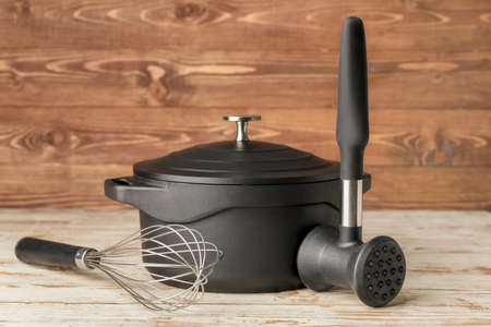 Cooking pot with whisk and hammer on wooden backgroundの写真素材