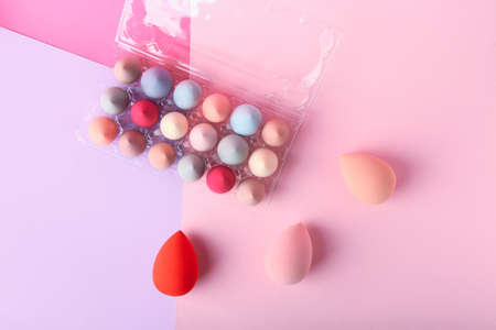 Plastic eggs holder with makeup sponges on color backgroundの写真素材