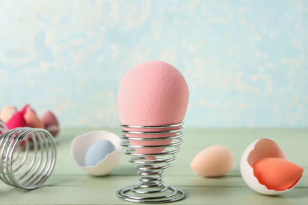 Creative composition with makeup sponges and eggs holders on table against color background, closeupの写真素材