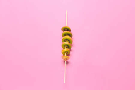 Cut ripe kiwi on stick against color backgroundの写真素材