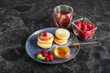 Plate with tasty cottage cheese pancakes, raspberry and honey on dark backgroundの写真素材