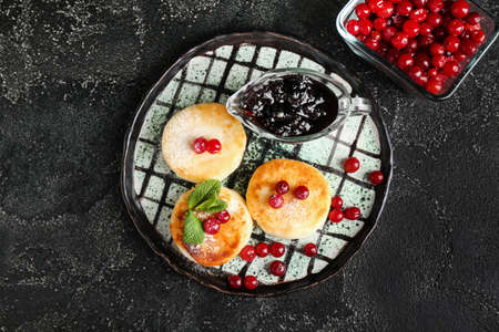 Plate with tasty cottage cheese pancakes. cranberry and jam on dark backgroundの写真素材