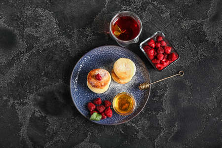 Plate with tasty cottage cheese pancakes, raspberry and honey on dark backgroundの写真素材