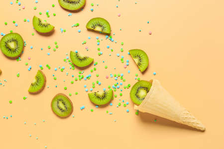 Composition with waffle cone and ripe kiwi on color backgroundの写真素材