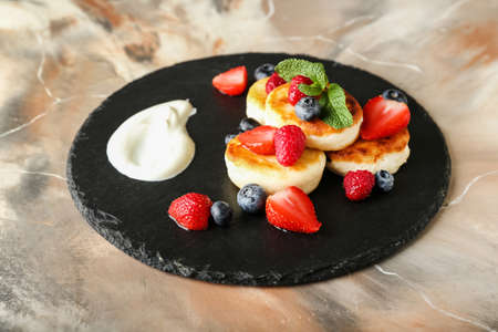 Slate plate with tasty cottage cheese pancakes and berries on grunge backgroundの写真素材