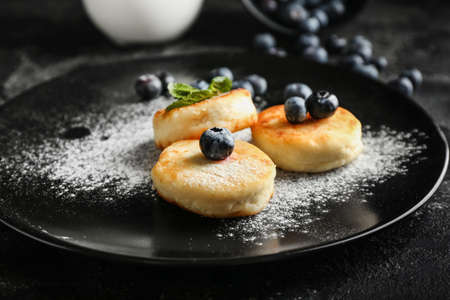Plate with tasty cottage cheese pancakes and blueberry on tableの写真素材