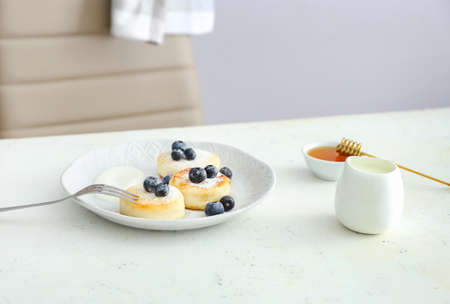 Plate with tasty cottage cheese pancakes and blueberry on tableの写真素材