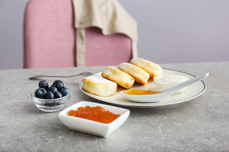 Plate with tasty cottage cheese pancakes on table