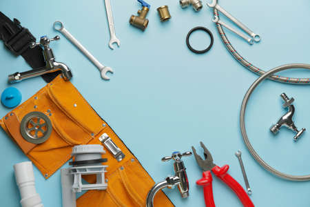 Frame made of plumber's items on color background