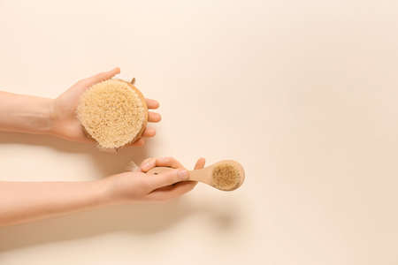 Female hands with massage brushes on color backgroundの写真素材