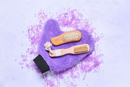 Composition with massage brushes, glove and sea salt on color background