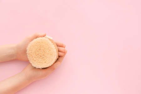 Female hands with massage brush on color backgroundの写真素材