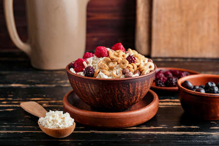 Bowl of cottage cheese with cereal rings and berries on dark wooden backgroundの写真素材