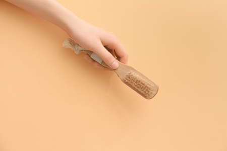 Female hand with massage brush on color backgroundの写真素材