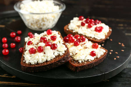 Bread with cottage cheese and red currants on dark wooden backgroundの写真素材