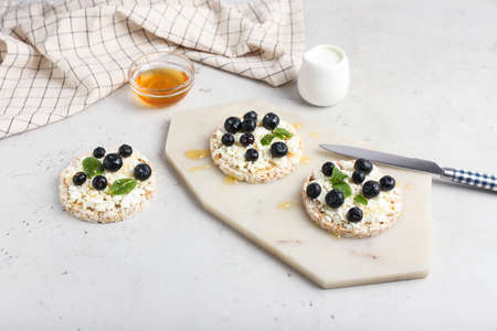 Crispbreads with cottage cheese and blueberries on light backgroundの写真素材