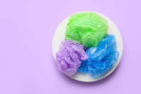 Plate with crumpled bags on color background. Environment pollution conceptの写真素材
