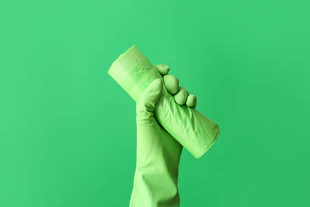 Hand in rubber glove with roll of garbage bag on color backgroundの写真素材