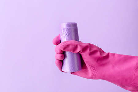 Hand in rubber glove with roll of garbage bag on color backgroundの写真素材
