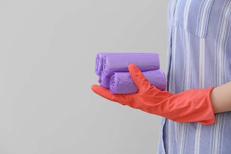 Woman holding rolls of garbage bags on light backgroundの写真素材