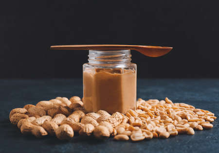 Jar and spoon with tasty peanut butter on color backgroundの写真素材