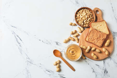 Jar and toast with tasty peanut butter on light backgroundの写真素材