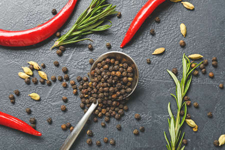 Spoon with peppercorns and different spices on dark backgroundの写真素材