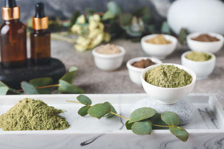 Composition with dry henna powder in bowls and bottles of essential oil on grunge background, closeupの写真素材