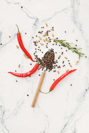 Spoon with peppercorns and different spices on light backgroundの写真素材