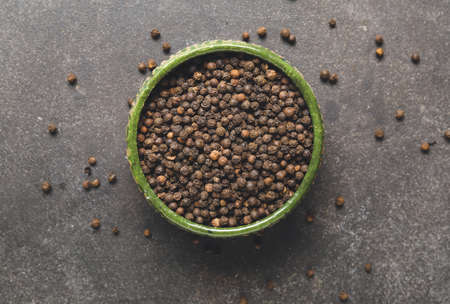 Bowl with peppercorns on dark background