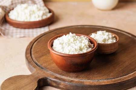 Bowls with cottage cheese on color background