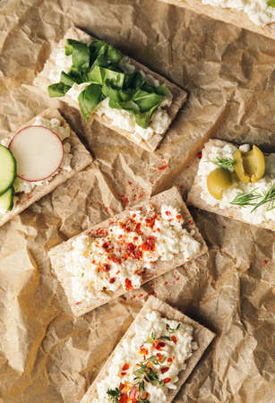 Crispbreads with cottage cheese and vegetables on parchment paper, closeupの写真素材